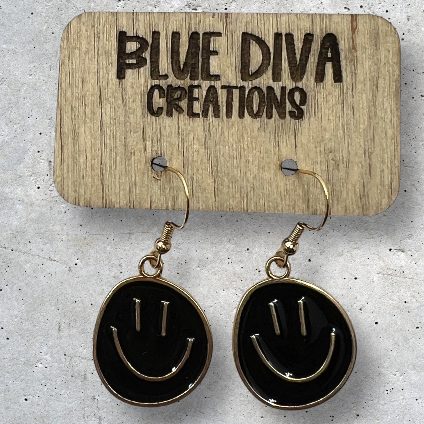 Photo of a pair or round metal black and gold smiley face dangle earrings