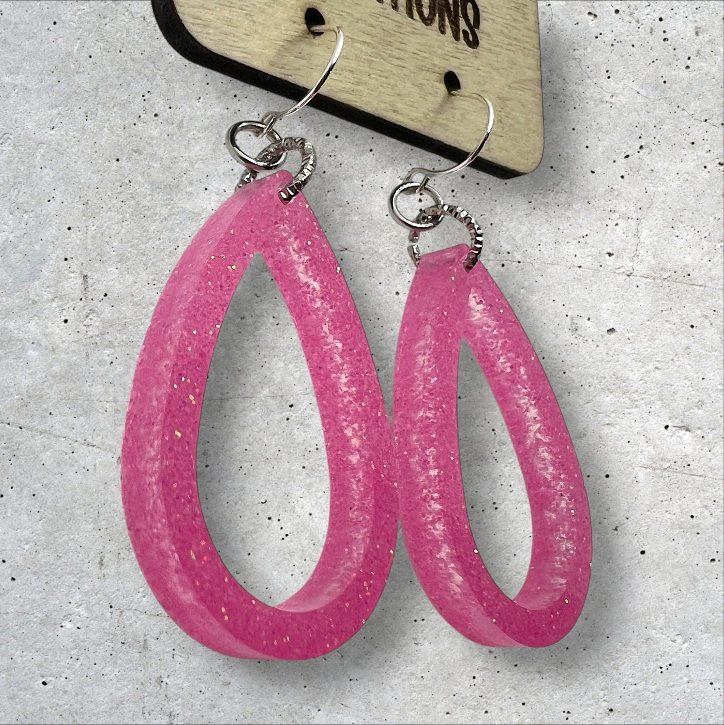 Side view of Light pink glitter open teardrop dangle resin earrings