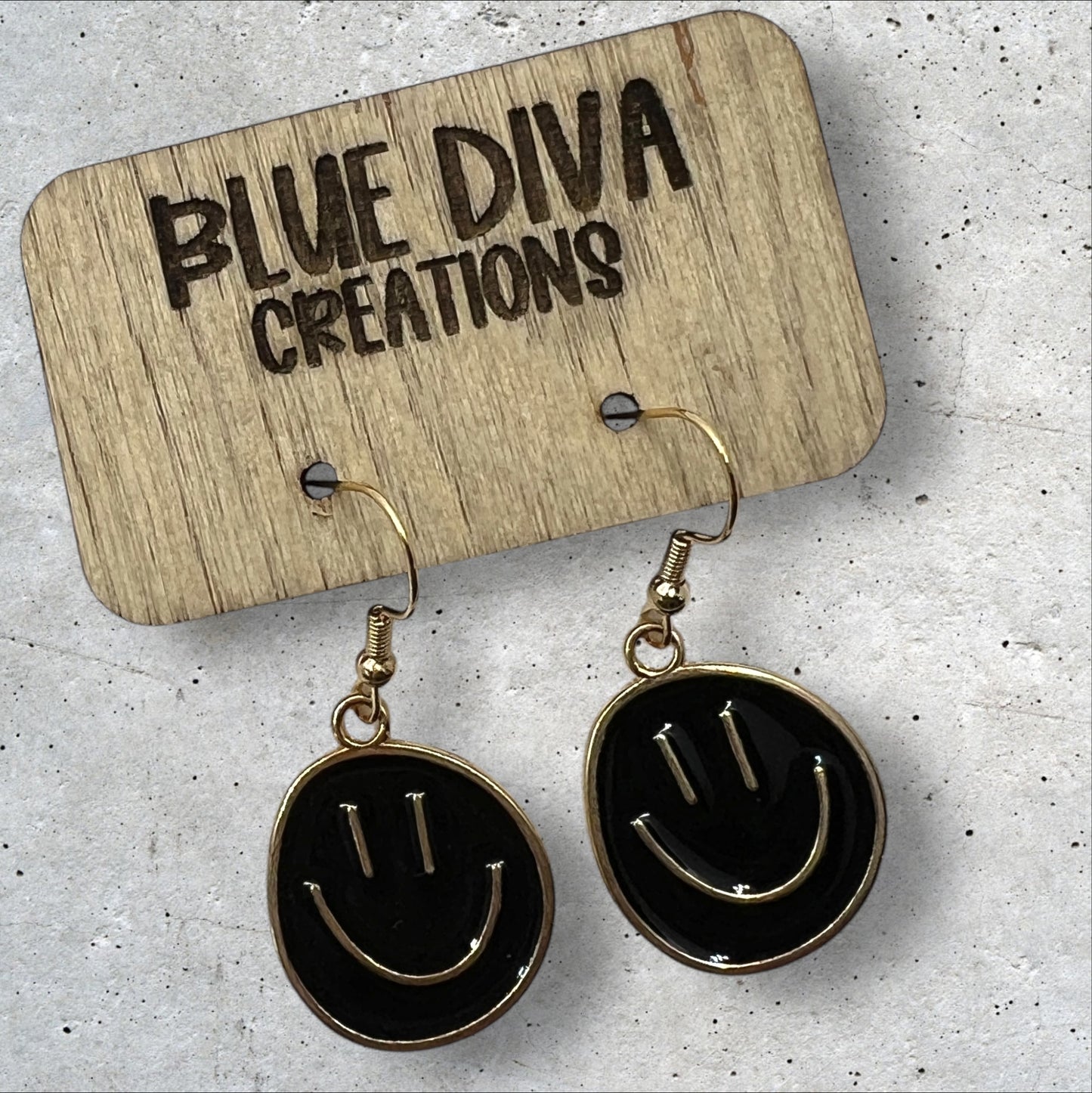 Photo of a pair or round metal black and gold smiley face dangle earrings