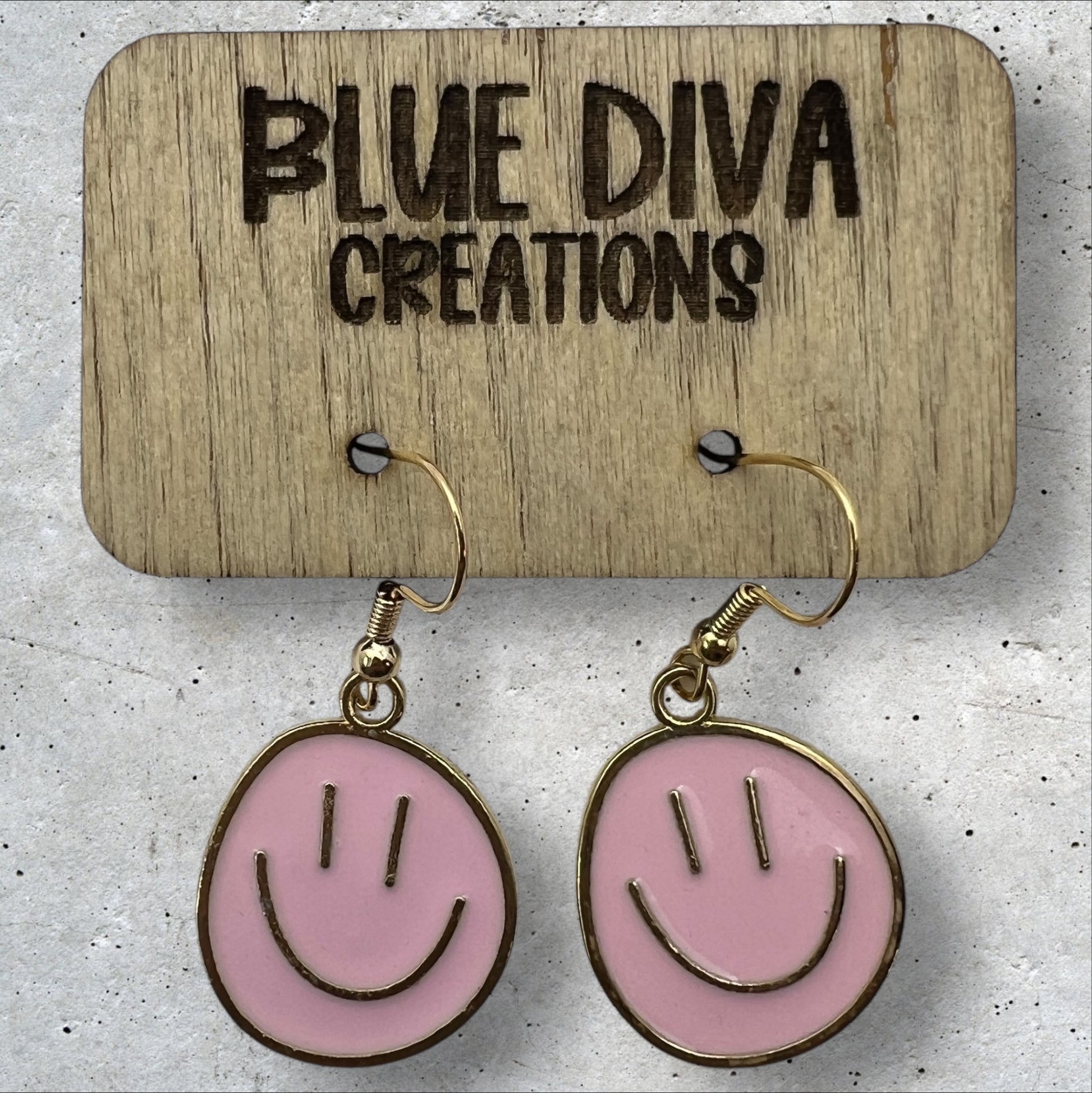 Photo of a pair or round metal light pink and gold smiley face dangle earrings 