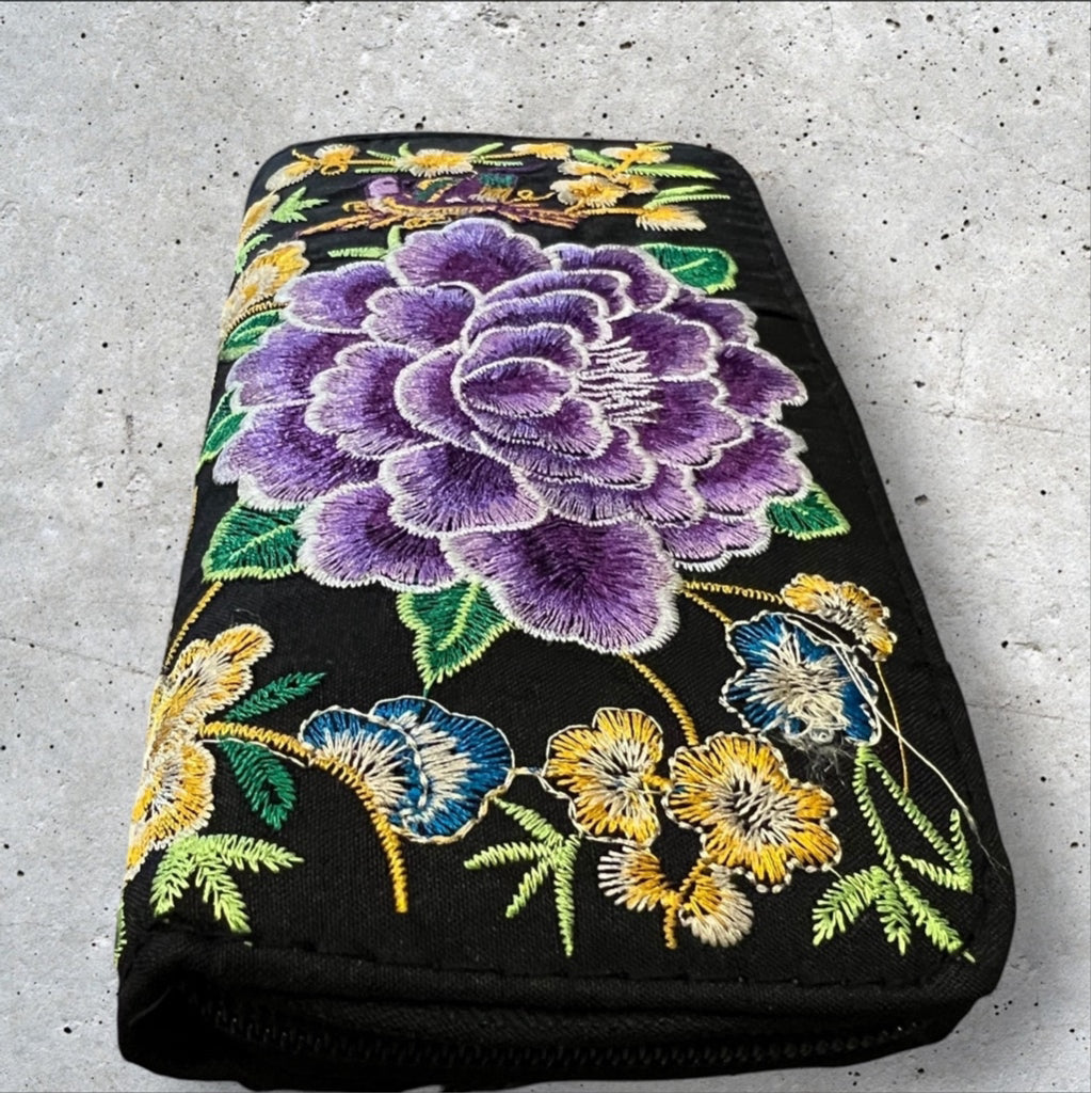 Black Fabric 8x4” zip around wallet with a vibrant purple embroidered flower and yellow embroidered flowers 