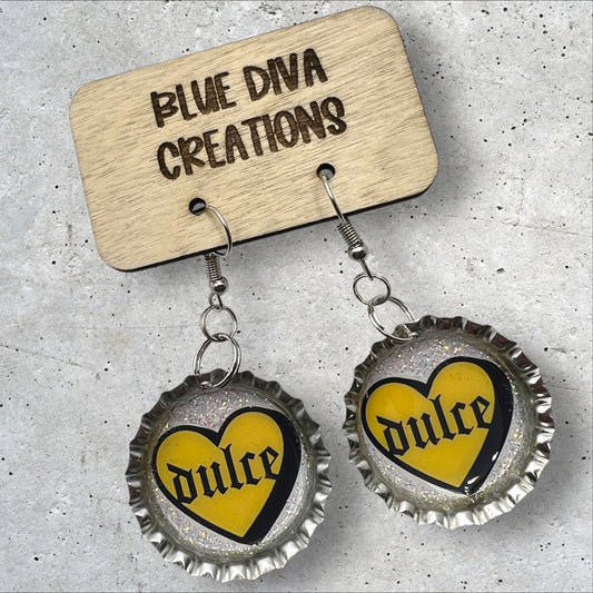 bottle cap earrings with image of a yellow heart with the Spanish words “Dulce” in the middle in gothic font